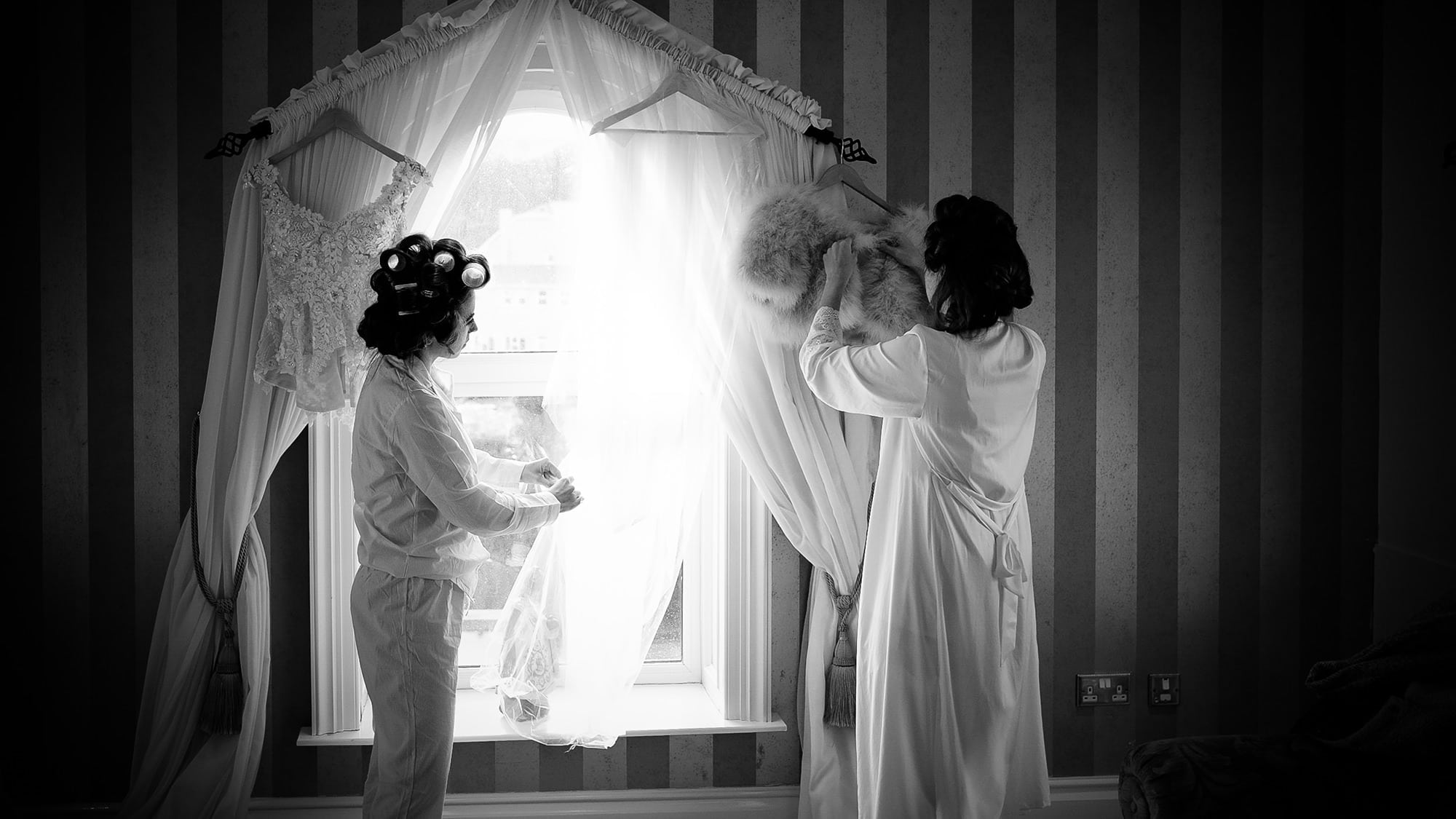 bridesmaids preparing dresses at window