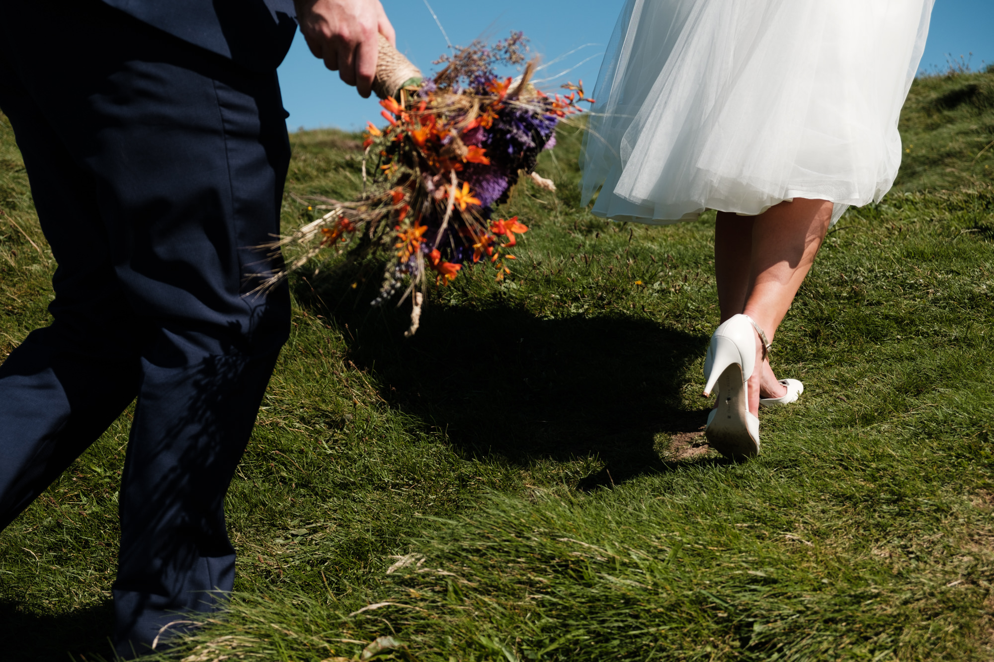 bride and groom running across grass